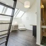 Stylish studio room in coliving space: cozy bed, sleek kitchen, contemporary bathroom